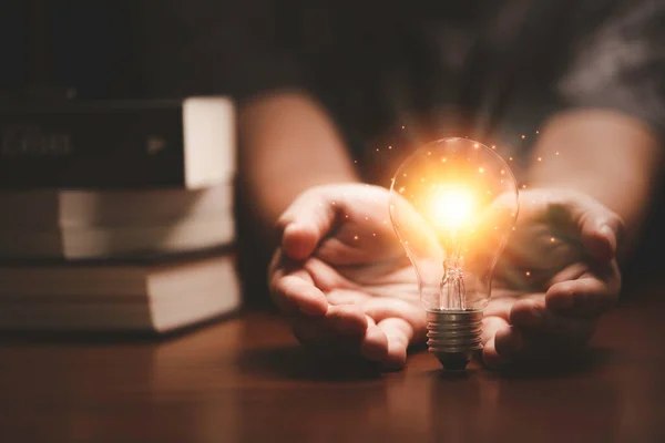 Businessman Holding Orange Light Glowing Lightbulb Infant Heap Books Study — стоковое фото