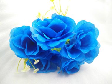 Yaprakları kumaştan yapılmış, sapı da izole edilmiş beyaz bir zemin üzerinde plastikten yapılmış mavi bir süs çiçeği.