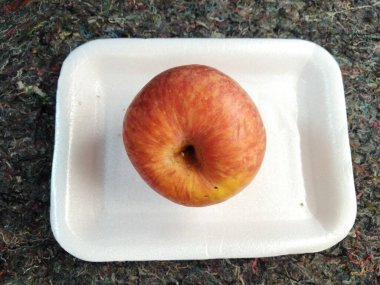 high view of one red apple placed on the carpet.Apples are known to be low in calories and contain a variety of vitamins and minerals, such as vitamin A, vitamin B6, vitamin C, and potassium.