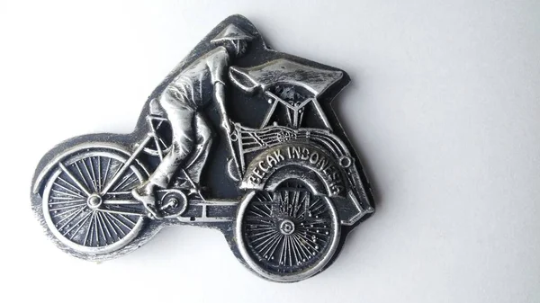 refrigerator magnet in the form of a rickshaw, pedicab is one of the means of transportation in Indonesia. fridge magnet isolated on a white background.high angle view.