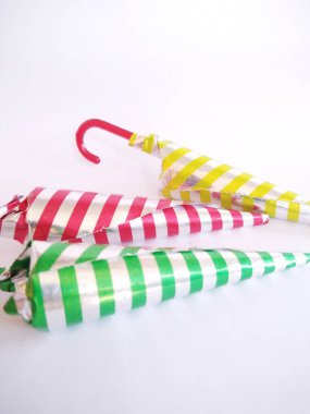 chocolate shaped like an umbrella wrapped in aluminum foil with a strip motif. isolated on a white background.close up.