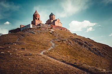 Scenic view of mountain trail to Tsminda Sameba - Holy Trinity Church near the Kazbegi, Gergeti village, Georgia. Vintage retro toning