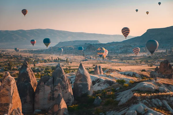 Cappadocia aerial sunrise landscape, colorful hot air balloons fly over cave house and famous fairy chimneys in Goreme national park. People enjoy wonderful aerial sun rise watching. Travel background