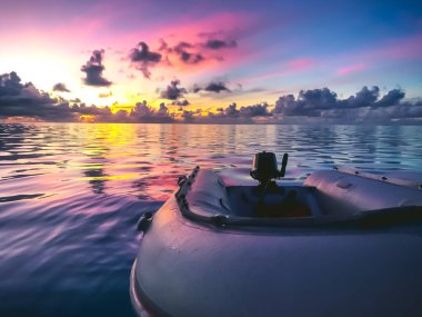 Tropik günbatımına karşı lastik tekne. Parlak pembe turuncu gökyüzü okyanus suyuna yansıyor. İnanılmaz doğal yaz manzarası. Seyahat, turizm, tatil