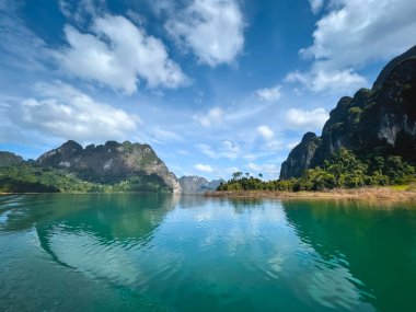 Dağlardaki Emerland su gölü. İnanılmaz doğal yaz manzarası. Göz kamaştırıcı doğal bir geçmiş. Popüler turistik bir yer. Seyahat, Cheow Larn Gölü 'nde turizm - KHAO SOK Ulusal Parkı, Tayland