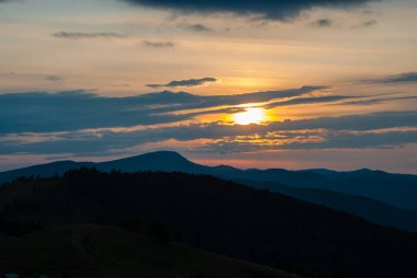 Gün batımında Karpat Dağları. Bulutlu akşam gökyüzü. Dağ manzarasına zıt. Uzak dağ zirvesi. Dağlarda sabah akşam