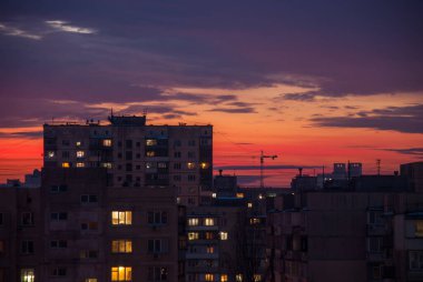 Akşam gökyüzünün arka planına karşı apartman binaları. Sovyet paneli çok katlı binaları harap etti. Akşamları işlevsiz konut alanı. Binaların pencerelerinde ışık var. Çatı katları. Ukrayna Kyiv Obolon