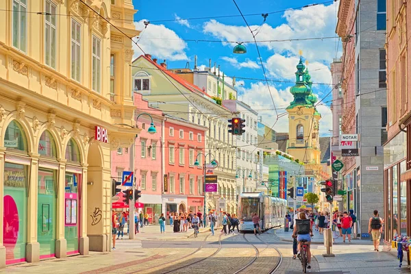 Linz - Haziran 2020, Avusturya: Yürüyen insanlar, dükkanlar, tramvay hatları ve bir tramvay ile şehrin ana caddesine bakın