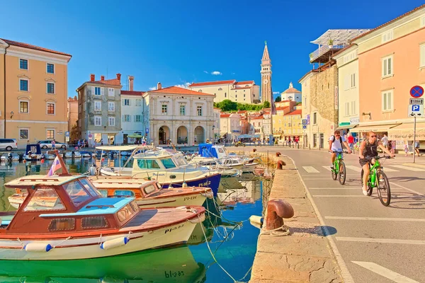 Piran - Temmuz 2020, Slovenya: Antik Slovenya 'nın Piran kentinin limanında, renkli teknelerin yakınındaki rıhtımda bisiklet süren bir çift
