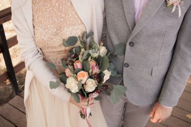 Bride and groom standing together and holding a bouquet of flowers