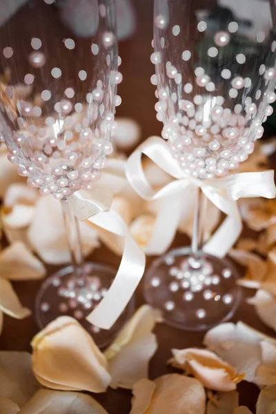 Wedding glasses with white pearls and rose petals around