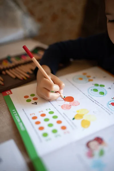 A child drawing in a workbook. Home education, home studying