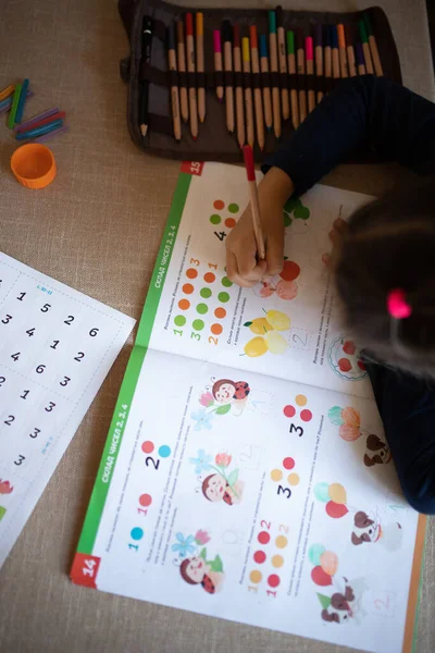 A child drawing in a workbook. Home education, home studying