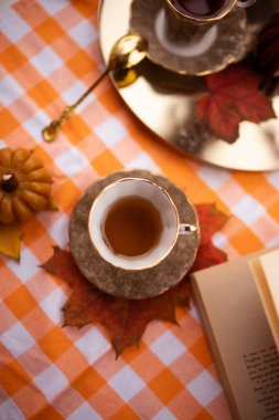 Balkabağı, çay fincanı, sonbahar yaprakları, çaydanlık, altın kaşık ve klasik kitap şeklinde mumlarla dolu bir sonbahar.