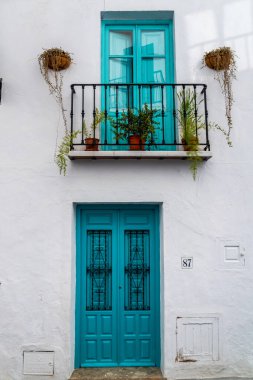 FRIGILIANA, SPAIN - January 28 2022: Streets of Frigiliana village. Beautiful white houses and small streets. Typically Andalusian town. White house with turquoise, aqua marine door and windows.