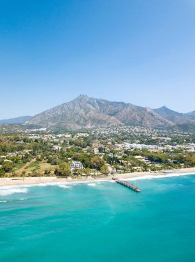 Unique aerial view of luxury and exclusive area in Marbella, golden mile beach, view of Puente Romano Bridge and in background famous La Concha mountain. Emerald water colour