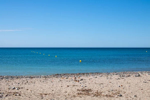 Mavi gökyüzü ve beyaz bulutlarıyla güzel bir sahil.