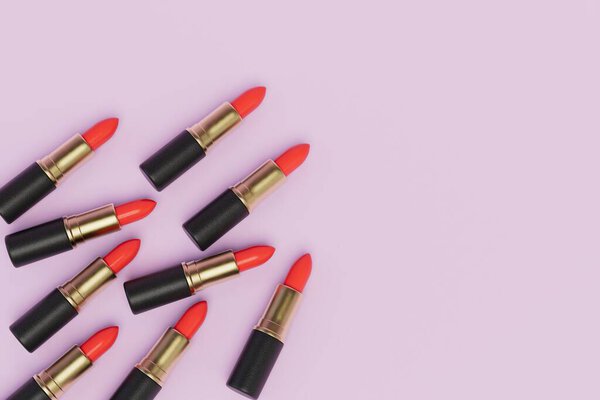 several tubes of red lipstick on a pink pastel background. copy paste, copy space. 3D render.