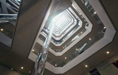 Boş modern bir binanın iç metale ve cam yapısına yukarıdan gelen ışığın olmadığı yerlerden bak.