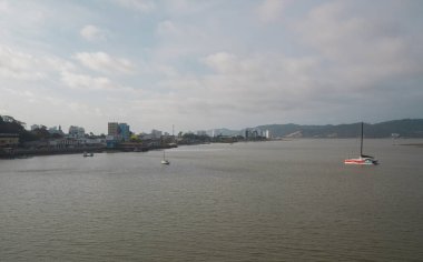 Bahia de Caraquez, Manabi / Ecuador - August 20 2022: Boats sailing on the Chone river with a panoramic view of the city in the background during sunset
