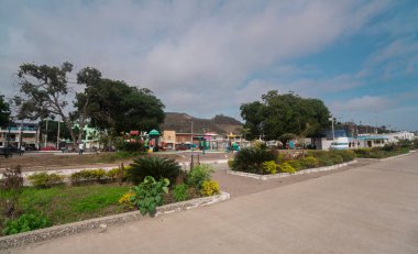 San Vicente, Manabi / Ecuador - August 20 2022: People walking through the central park with trees and playgrounds on a sunny day