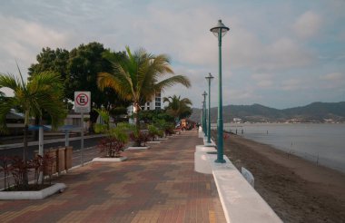 Bahia de Caraquez, Manabi / Ecuador - August 20 2022: People walking on the boardwalk of the city next to the beach on a cloudy day