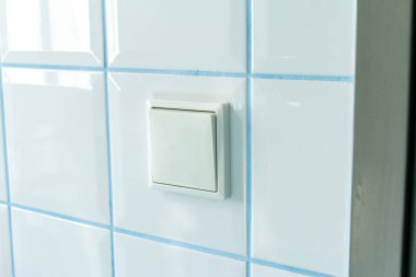 switch in the bathroom against the background of tiles