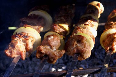 Coocking meat and onions on charcoal on summer day