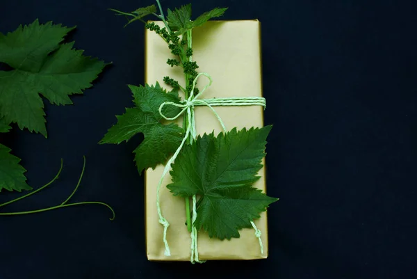 Gold color paper in gift wrapping with a branch of grapes on a black background