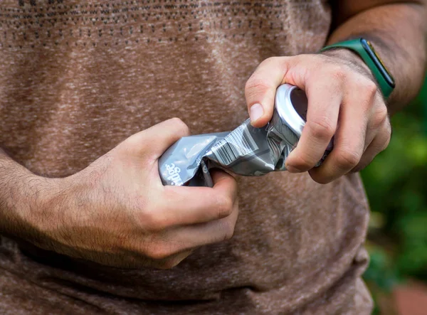 Squeezing a tin can by a man on the street, for its further disposal