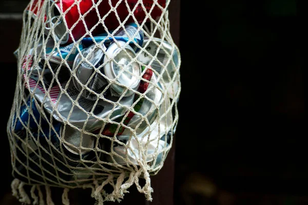 Drink cans crumpled and folded into a rag net for disposal