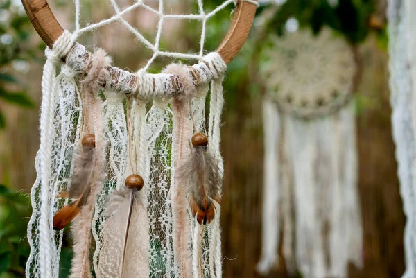 Dream catchers crocheted from threads on a wooden base decorated with lace, threads, feathers and wooden beads outdoors