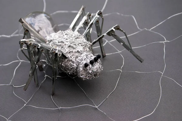 This metal spider is made with a light bulb, umbrella needles, metal wire, beads and metal shavings with a wire web