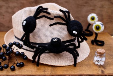 Bir şapkada üç siyah keçe kesesi, keçeli gözler, bir kavanoz göz ve ahşap bir arka planda siyah pinoplast üzümü.