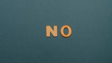 Wooden letters on plain colored background with the word written in English: No