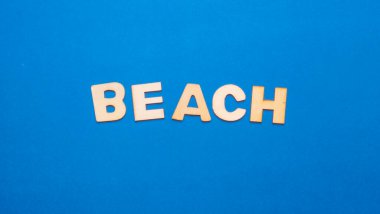 Wooden letters on plain colored background with the word written in English: Beach