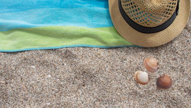 Yellow straw hat towel shade of blue and green colors on white sand