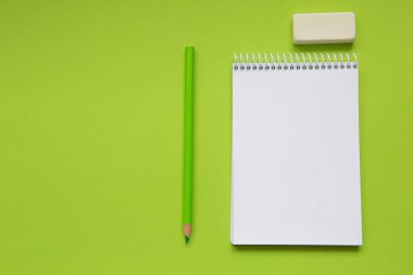 Blank notepad with green pencil on light green background
