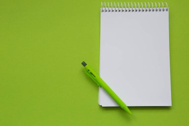 Blank notepad with green pencil on light green background