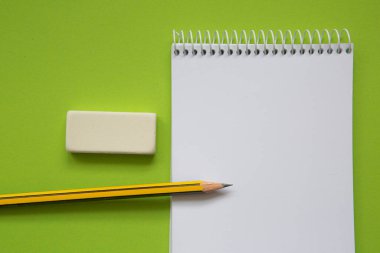Blank notepad with pencil on light green background