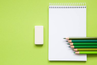 blank notebook with pencils different shades of green on light green background