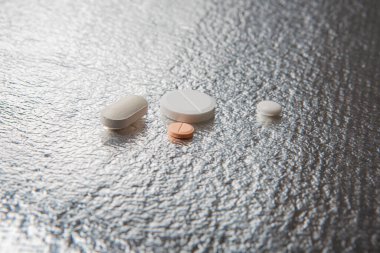 Different medicines and pills on silver colored background