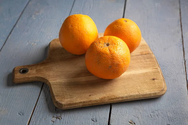 Three big oranges on wooden board