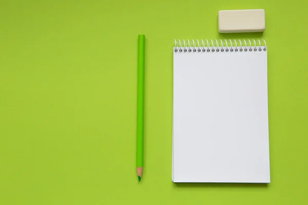 Blank notepad with green pencil on light green background