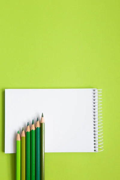 blank notebook with pencils different shades of green on light green background