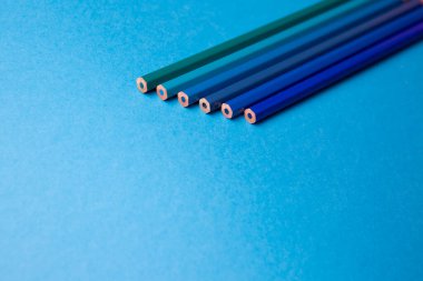 Wooden pencils of different shades of blue on a blue background