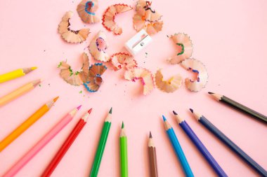 colored pencils next to sharpener on light pink background