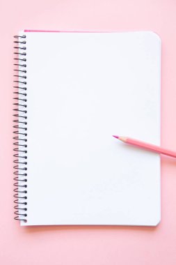pink pencil on notepad with blank page on pink background