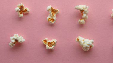 Popcorn arranged in order with a pattern on light pink background