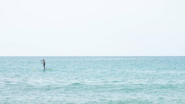 Silhouette of a man kayaking in the distance on the waters of the Mediterranean Sea